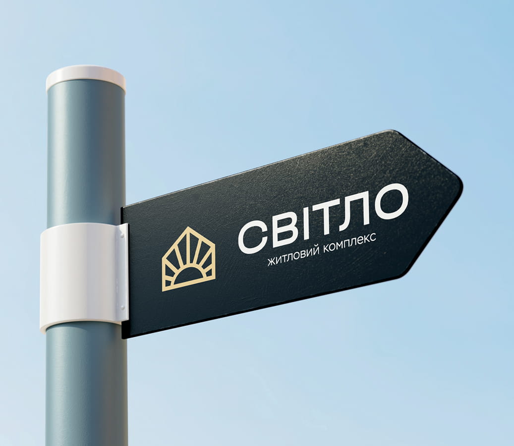Signpost reading 'СВІТЛО' (житловий комплекс) mounted on a pole against a blue sky.