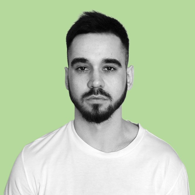 Portrait of a man with short dark hair and a beard, wearing a white t-shirt, against a light green background.
