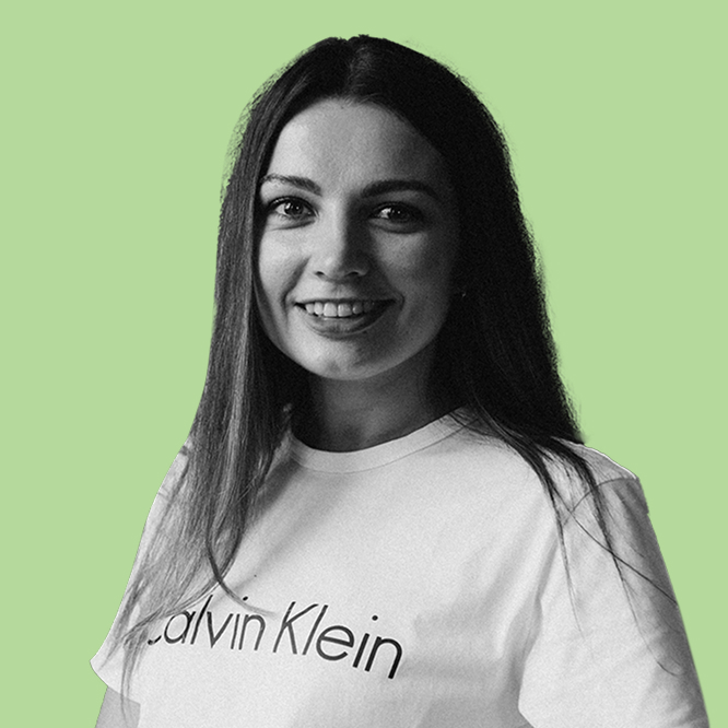 Smiling woman with long dark hair wearing a white Calvin Klein T-shirt against a light green background.