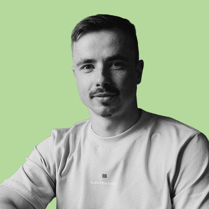 Portrait of a man with short hair and a mustache, wearing a light t-shirt, against a pale green background.