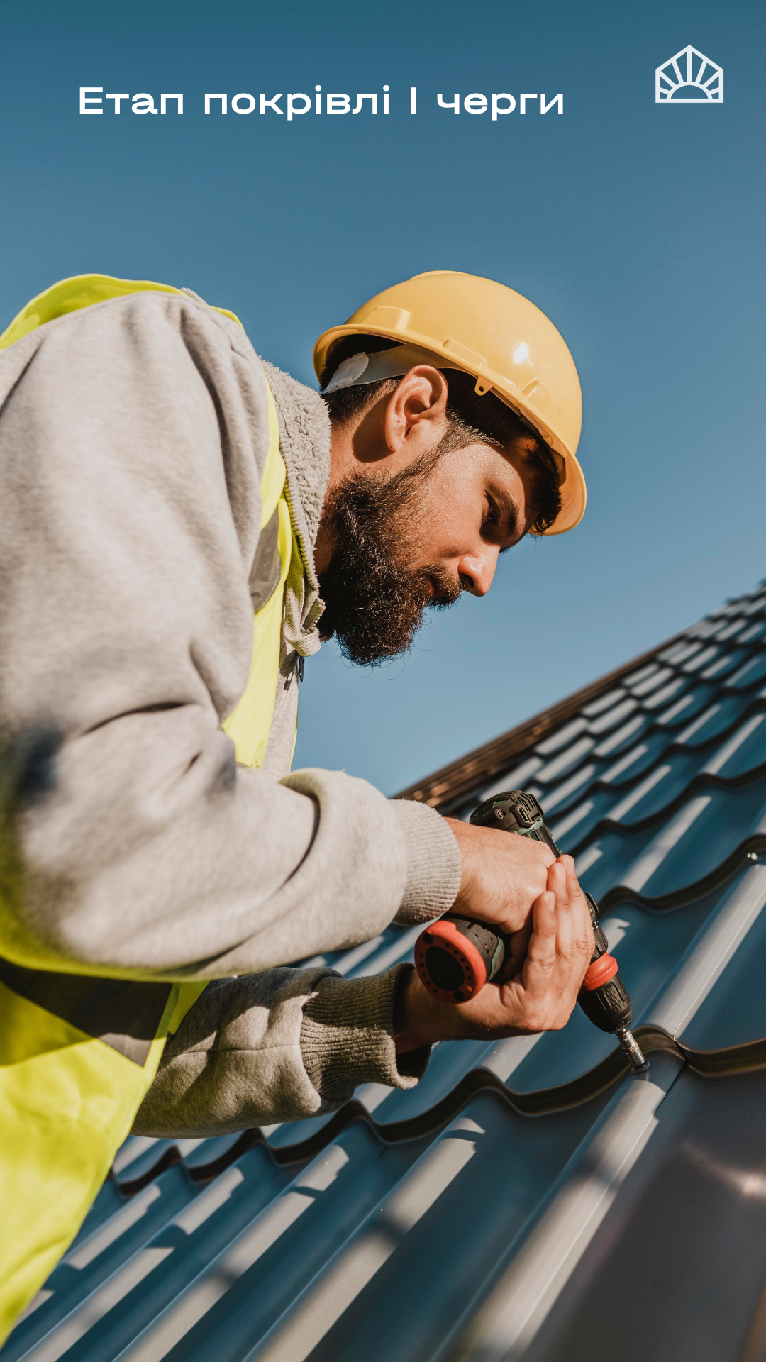 Worker in a yellow hard hat and high-visibility vest using a power drill on a metal roof under clear blue sky.