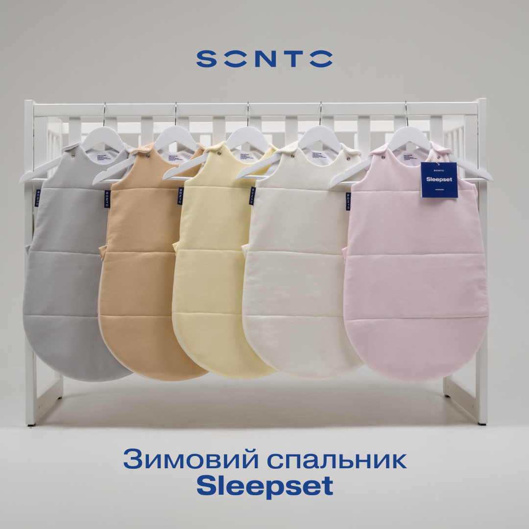 Row of pastel baby sleeping sacks hanging on a white rack in a showroom; Sleepset branding and Cyrillic caption visible below.