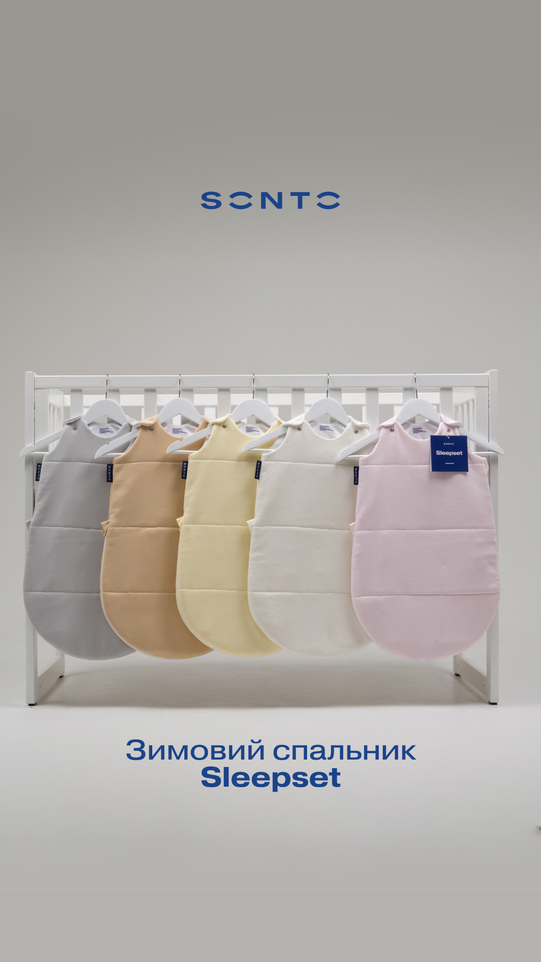 Row of pastel baby sleep sacks hanging on a white rack in a showroom.