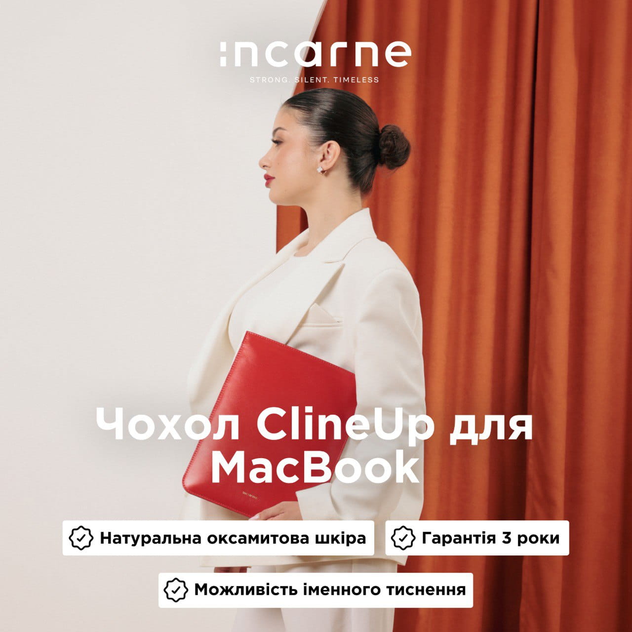Profile of a woman in a white suit holding a red MacBook sleeve against orange curtains; fashion advertisement with Incarne branding.