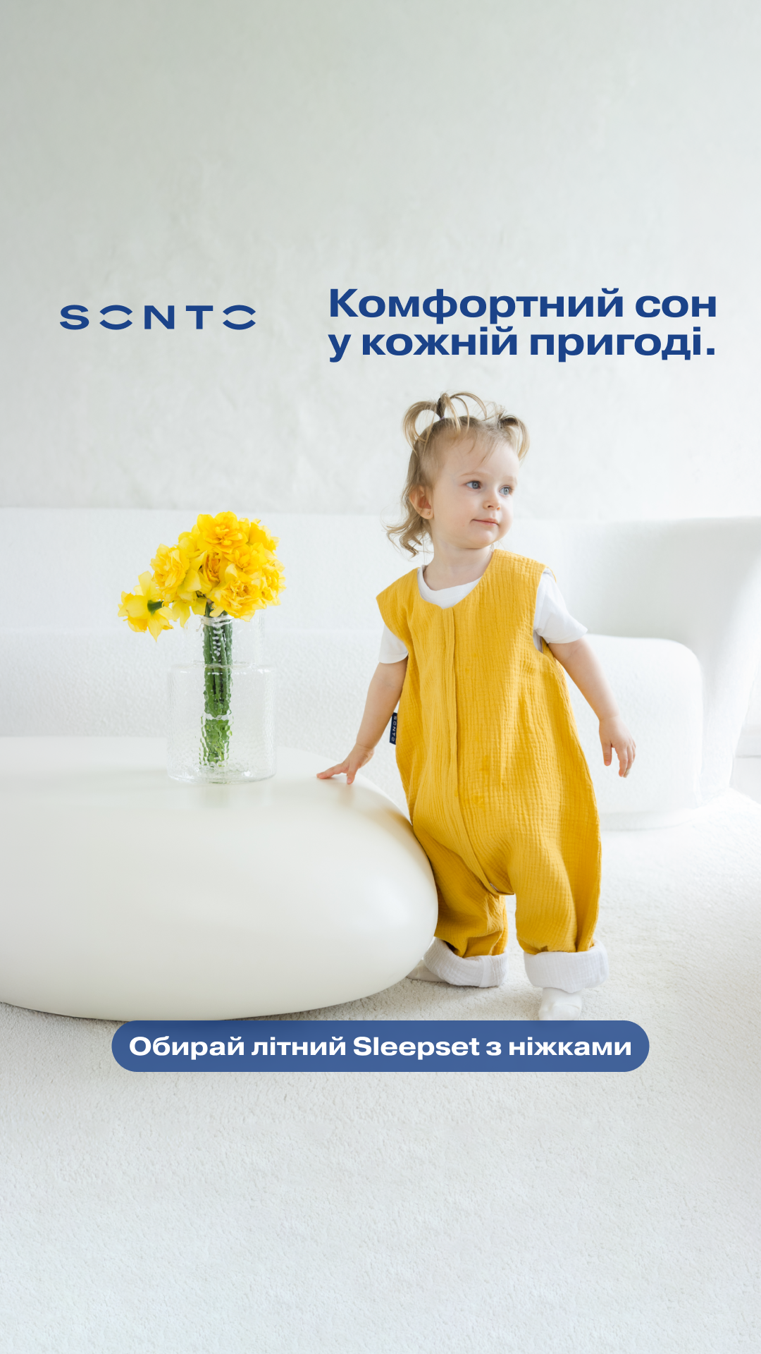 Child in a mustard yellow sleepsuit stands beside a vase of yellow flowers in a bright room; Ukrainian text reads 'Comfortable sleep in every adventure' with a blue rounded CTA at the bottom.